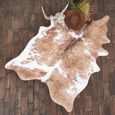 a brown and white cowhide rug on a wooden floor with pineconis in the center