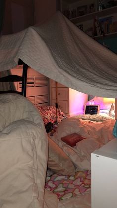 a bed with white sheets and pillows under a canopy in a room that is lit up