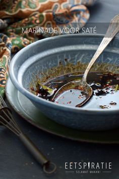 a bowl filled with oil and spoons on top of a table