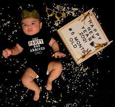 a baby wearing a party shirt next to a sign