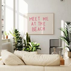 a living room with couches, plants and a sign that says meet me at the beach