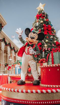 a mickey mouse statue in front of a christmas tree at the disney world holiday decorations