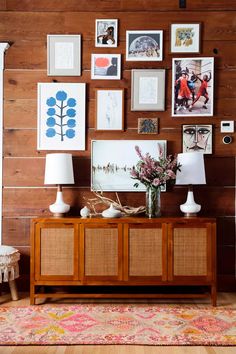 a living room with pictures on the wall and a vase full of flowers in front of it