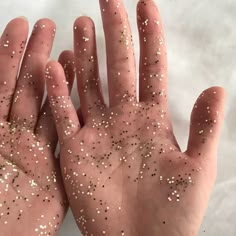 a person's hand covered in white and gold sprinkles on it