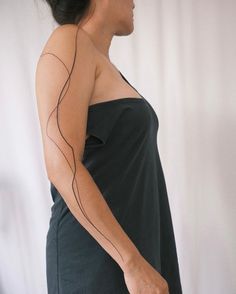 a woman wearing a black dress with lines drawn on her arm