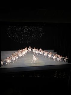 a group of ballet dancers on stage in the dark