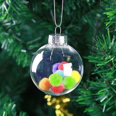 a glass ornament hanging from a tree filled with pom - poms