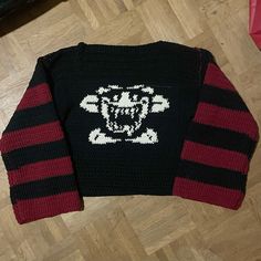 a sweater with a skull and crossbones on it sitting on top of a wooden floor