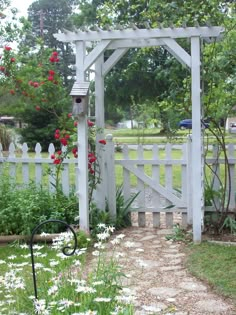 a garden with flowers and a white picket fence in the background is an open gate