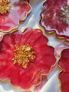 four red and gold flower shaped cookies sitting on top of a white tablecloth covered table