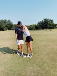 a man and woman standing on top of a lush green field next to each other