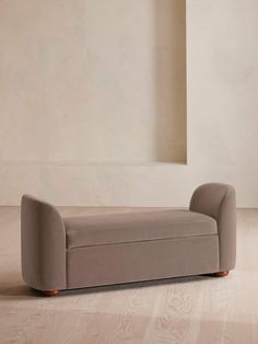 a grey couch sitting on top of a hard wood floor next to a white wall