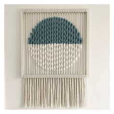 a wall hanging made out of yarn with a blue and white circle on the side