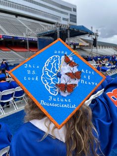 a woman wearing a blue graduation cap with butterflies on it