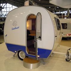 a white and blue trailer is on display in a showroom with other vehicles behind it