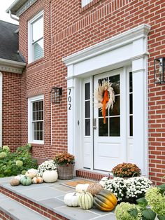 a front porch decorated with pumpkins and gourds