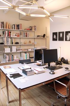 a desk with two computers on it in front of bookshelves and shelves full of books