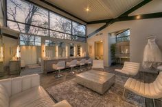 a living room filled with lots of white furniture and large windows over the top of it