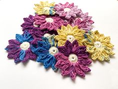 small crocheted flowers sitting on top of a white tablecloth covered floor next to each other