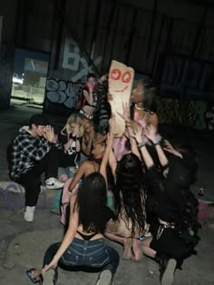 a group of people sitting on the ground with their arms in the air and one person holding up a sign