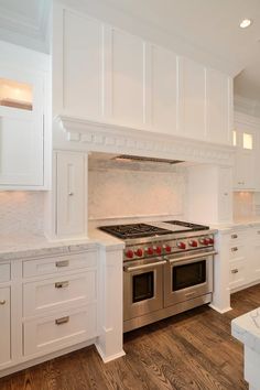 a kitchen with white cabinets and stainless steel stove top oven in the middle of it