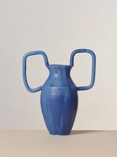 a blue vase sitting on top of a table next to a white wall and floor