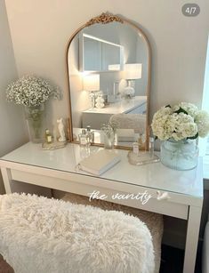 a white vanity with a mirror and flowers on it