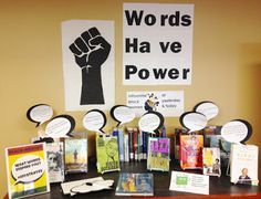 there are many books and pamphlets on the desk with signs above them that say words have power