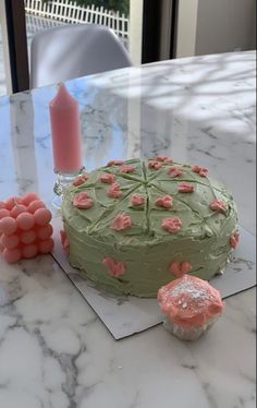 a green cake sitting on top of a table next to cupcakes and candles