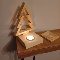 a wooden table topped with a candle and a small tree shaped object on top of it