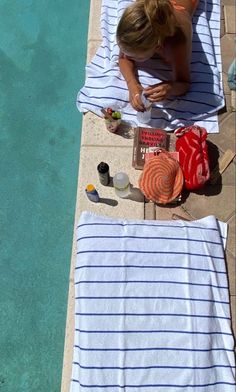 a woman laying on top of a towel next to a pool