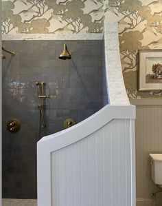 a bathroom with a toilet, shower and sink next to a painting on the wall