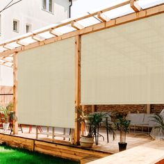 an outdoor patio area with blinds on the side and green grass in front of it