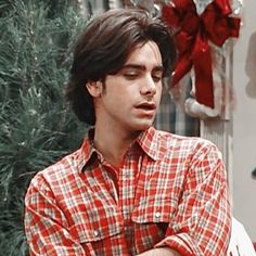 the young man is sitting in front of a christmas tree