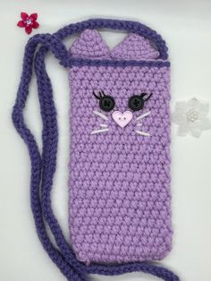 a purple crocheted cell phone case with a cat face on the front and side