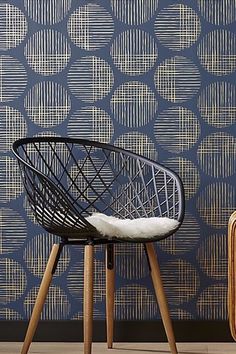 a black chair sitting in front of a blue wall with white circles on the wall