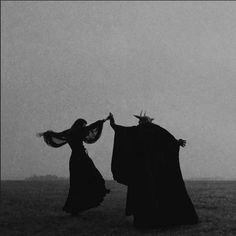 two women dressed in black are holding hands and facing each other with their arms outstretched