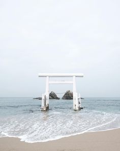 a white structure sitting on top of a sandy beach next to the ocean