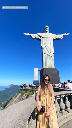 a woman standing in front of the statue of christe on top of a hill