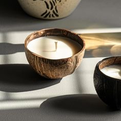 two coconuts sitting next to a candle on a table with the light coming in