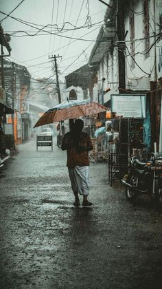 a person holding an umbrella walking down a street in the rain on a rainy day