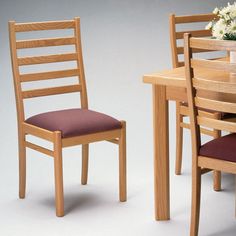 a wooden table with two chairs and a vase filled with flowers on top of it