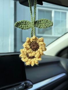 a crocheted sunflower hanging from the dashboard of a car