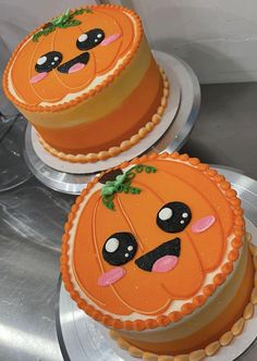 two decorated cakes sitting on top of each other in the shape of jack - o - lantern faces