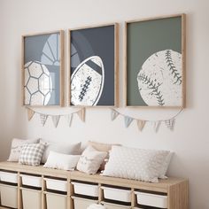 three framed sports pictures hang on the wall above a bench with pillows and storage bins