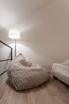 a large bean bag chair sitting on top of a hard wood floor next to a bed