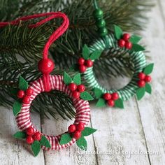 two christmas wreaths made out of yarn and beaded with holly leaves on them