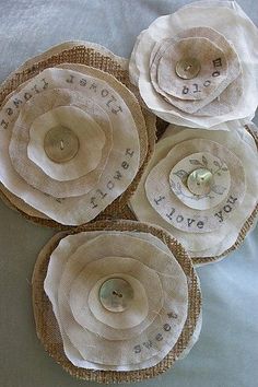 four burlap flowers with words on them