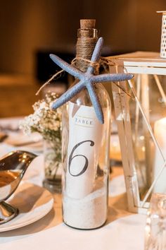 a bottle with sand inside sitting on top of a table next to a candle holder