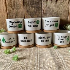 six ceramic planters with sayings on them sitting next to succulent plants